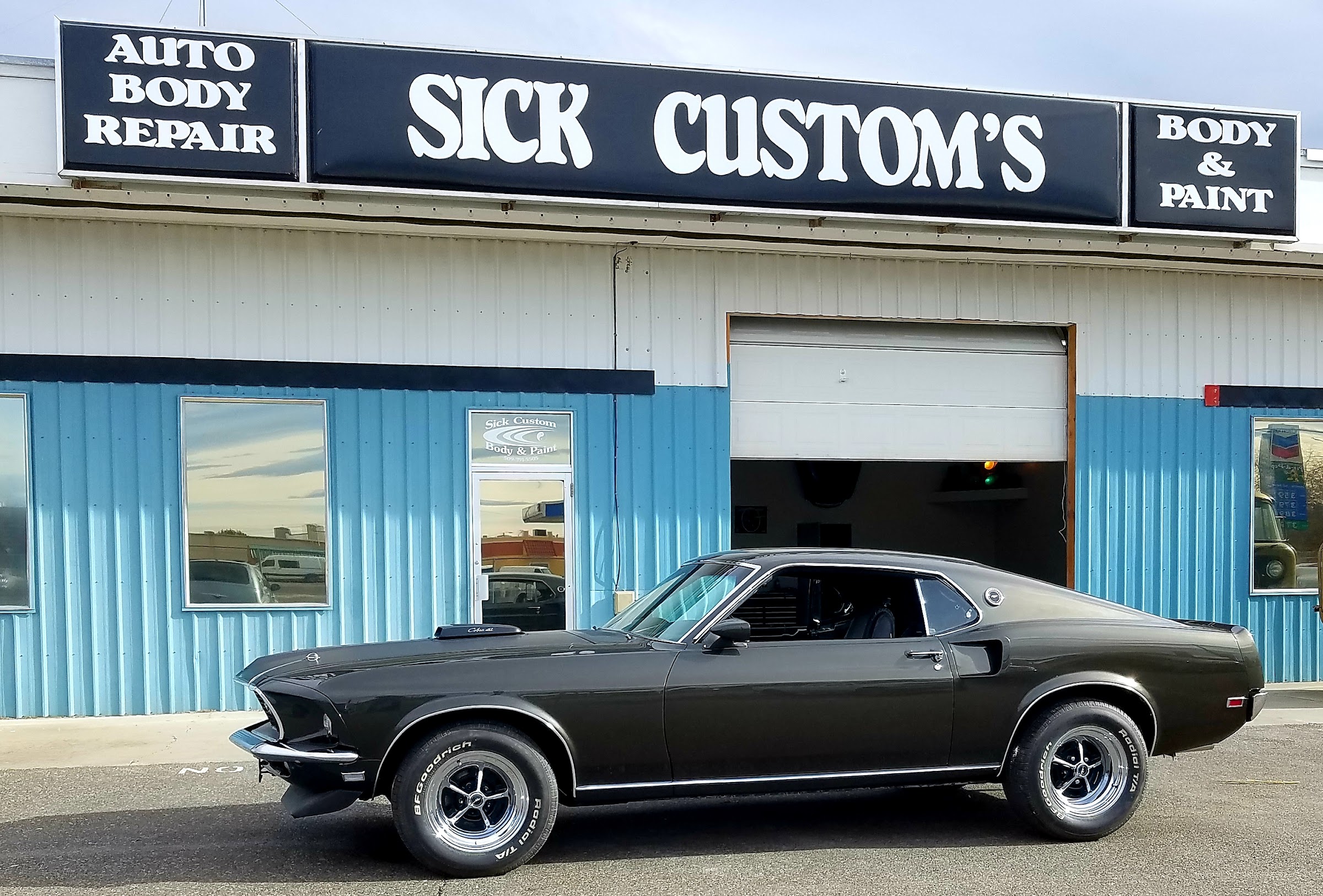 A 1969 Ford Mustang Mach 1 fastback in front of the Sick Custom Collision shop in Sunnyside